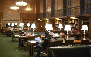 Interior of Yale library with lights on tables.