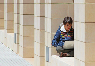 Student sitting outside with laptop.